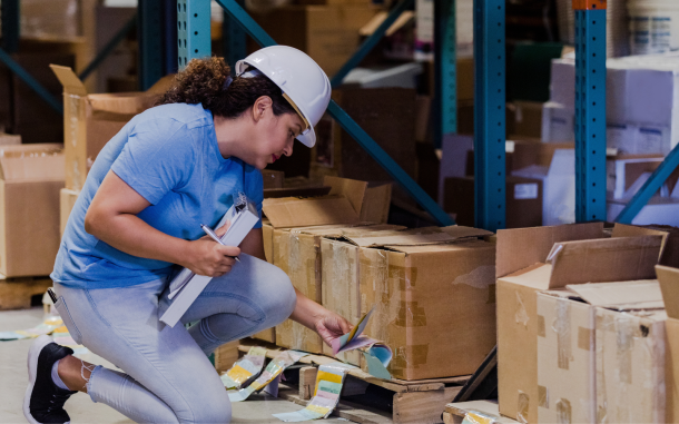 Image of a worker in a hard hat reading the label on a box